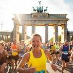 Group of happy marathon runners in front of Brandenburg Gate in Berlin